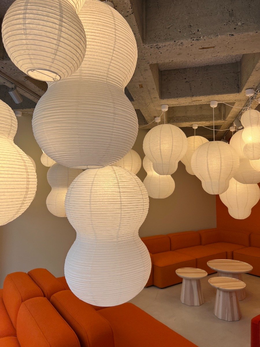 Large clusters of rice paper light shades over orange sofas
